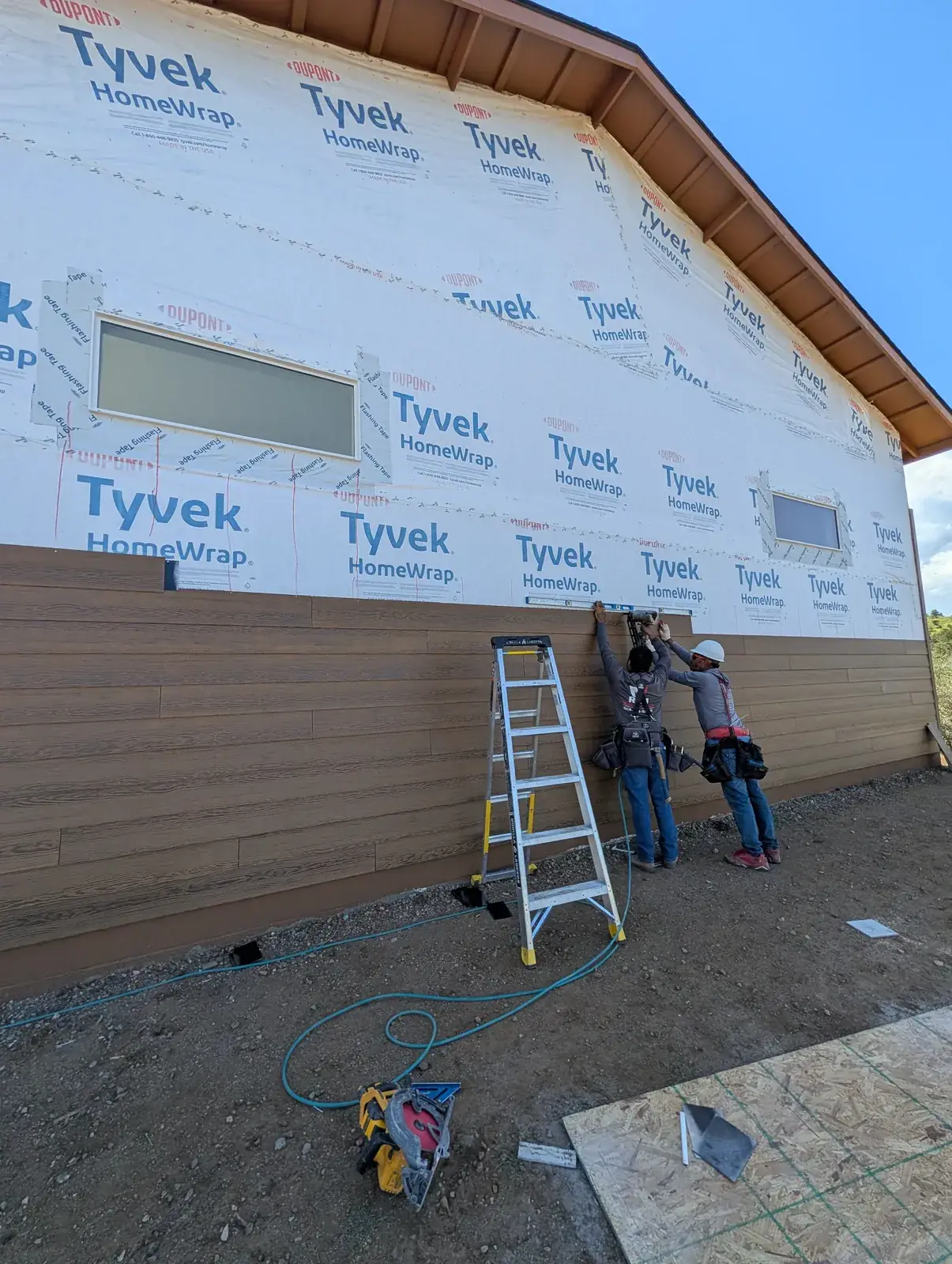 Crew installing lap siding over house wrap on a new home
